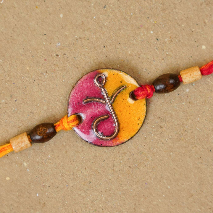 Handmade Round Ganesh Copper Enamel Rakhi With Chocolates & Roli Chawal