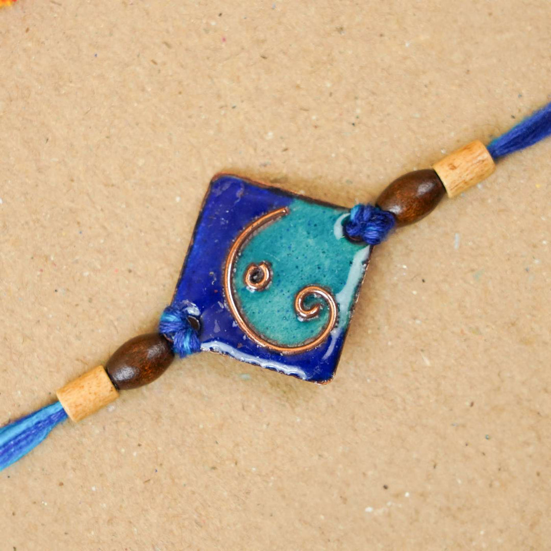 Handmade Geometric Ganesha Blue Copper Enamel Rakhi With Chocolates & Roli Chawal