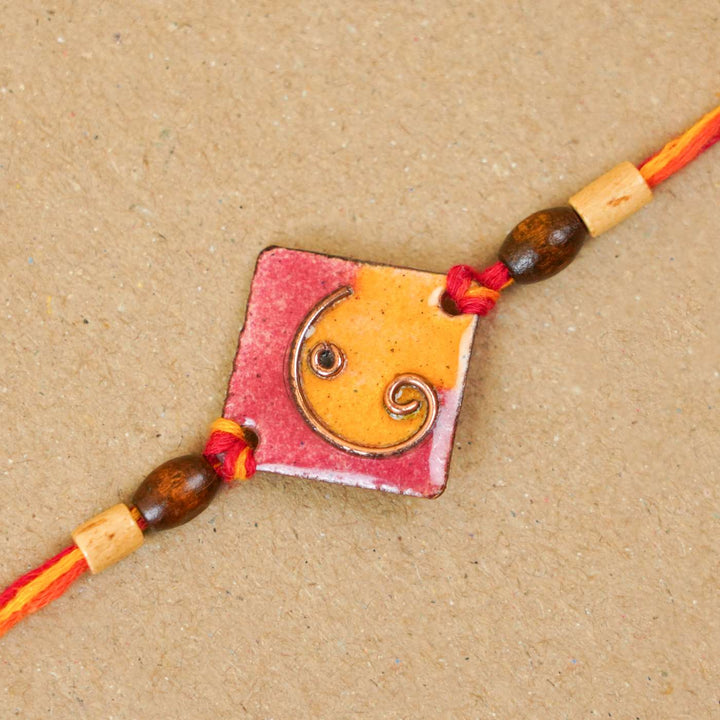 Handmade Square Ganesh Copper Enamel Rakhi With Chocolates & Roli Chawal