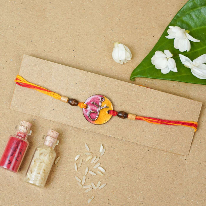 Handmade Round Ganesh Copper Enamel Rakhi With Chocolates & Roli Chawal